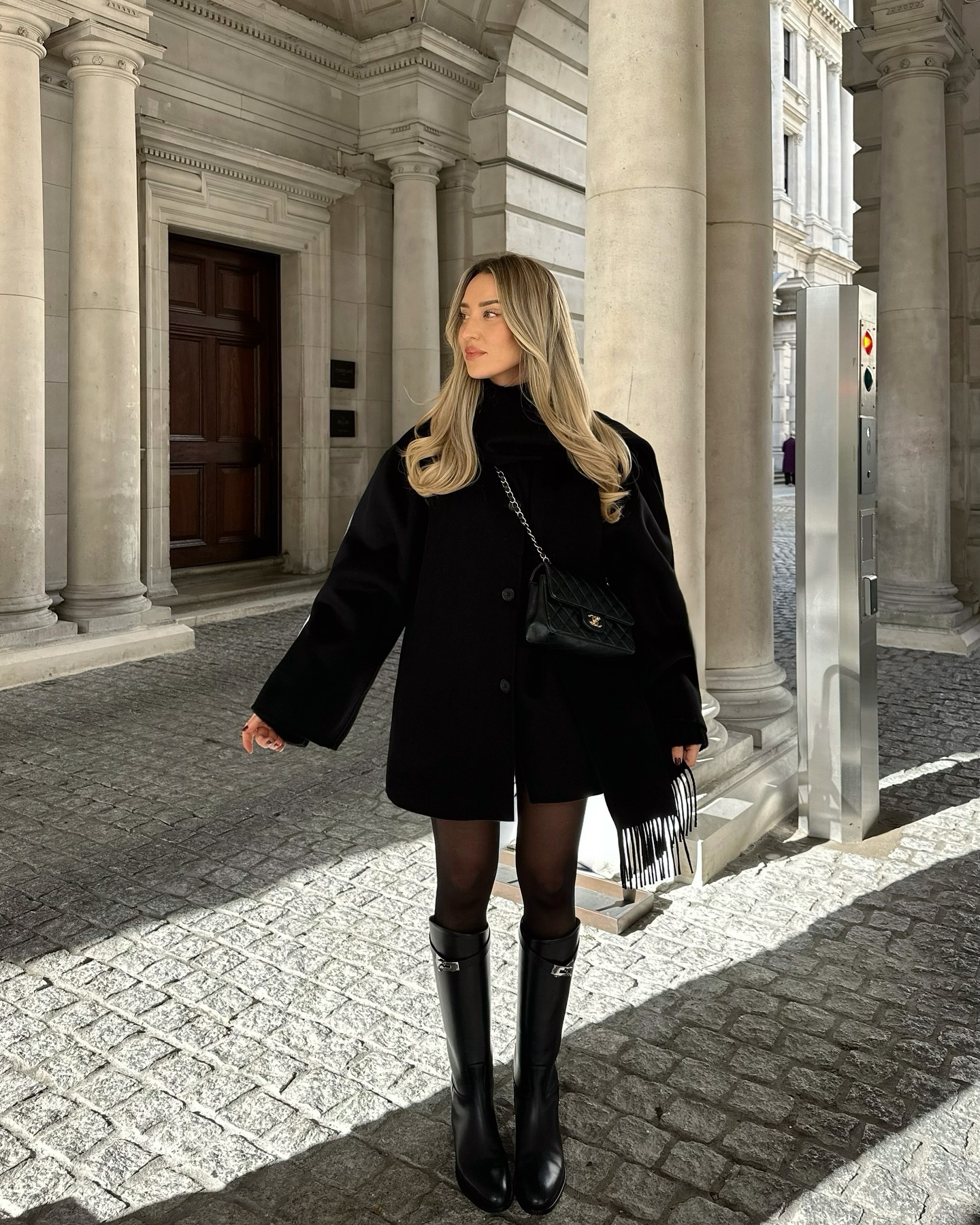 Freya Killin outfit of black shorts, black sweatert, black coat, black boots and bag